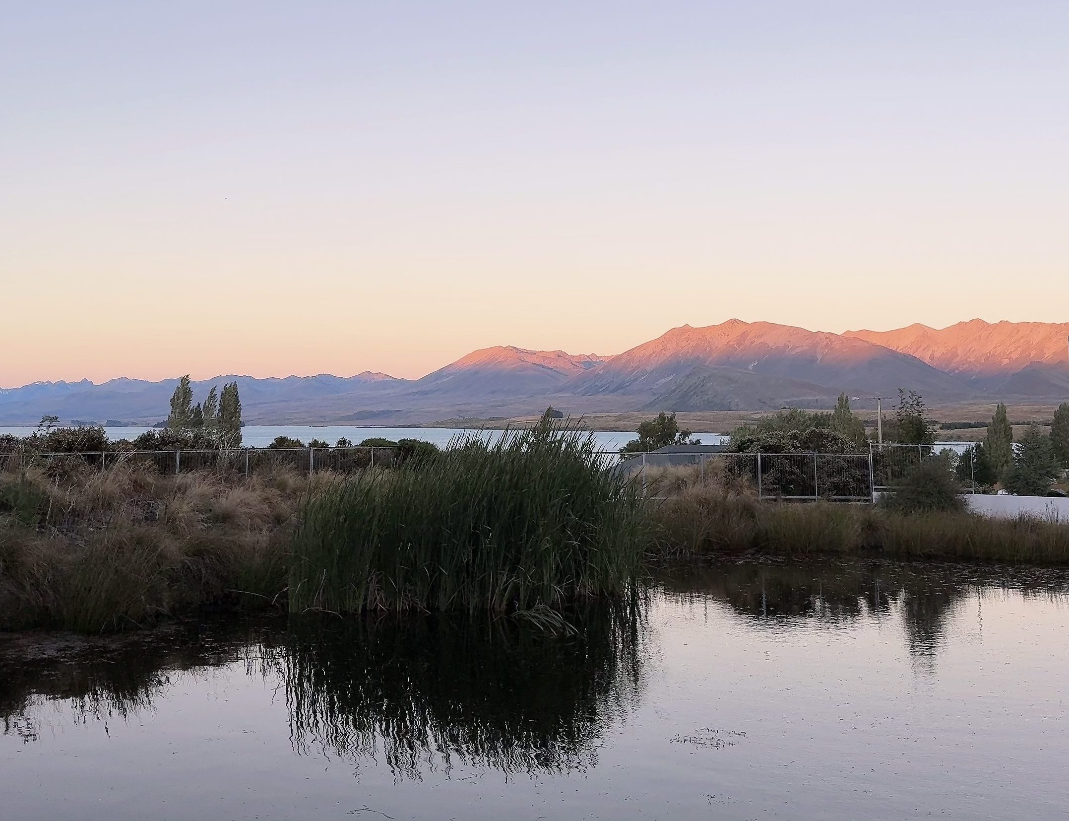 Still lake at sunset, viewed quietly from the shore during slow travel
